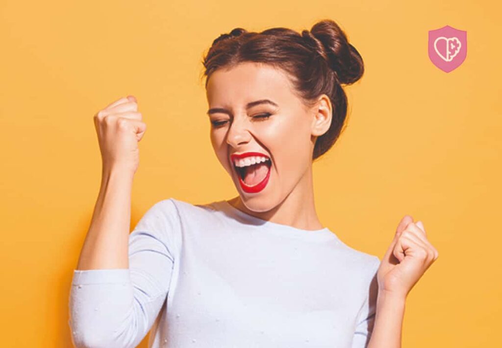 Mujer sonriendo y feliz - Mujer pintando cara feliz en una pared amarilla - Supera la ansiedad: Descubre el camino hacia la calma y el bienestar emocional