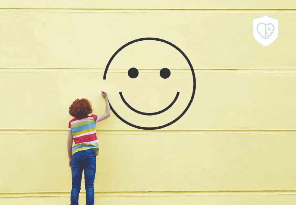 Mujer pintando cara feliz en una pared amarilla - Supera la ansiedad: Descubre el camino hacia la calma y el bienestar emocional